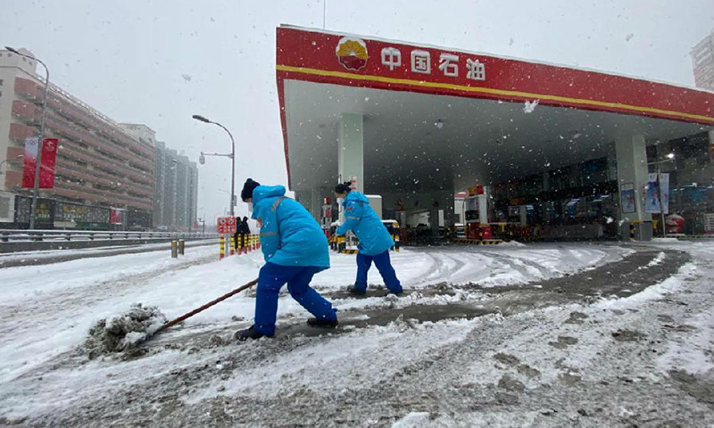  2月13日，中央氣象臺(tái)繼續(xù)發(fā)布暴雪藍(lán)色預(yù)警。大雪紛飛、氣溫驟降，讓冬季保供的步伐越發(fā)急促。不管是在保障北京冬奧的加油站，還是在全力保障眾多大中城市供氣的長(zhǎng)慶油田，不管是在繞29道彎山路的博孜1202井邊，還是在環(huán)準(zhǔn)噶爾盆地四千多公里油氣戰(zhàn)線上，中國(guó)石油員工不懼嚴(yán)寒堅(jiān)守一線，用安全保供為萬(wàn)戶(hù)千家送去溫暖。圖為距離鳥(niǎo)巢最近的石大第一加油站員工正在清雪。